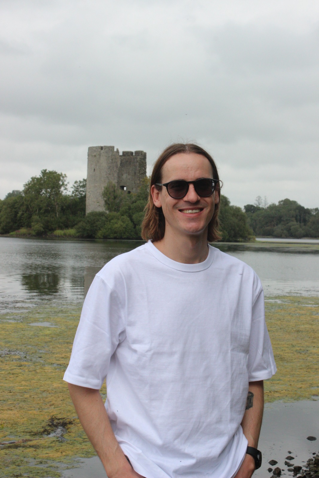 Kyle van Niekerk standing outdoors with a castle and lake in the background